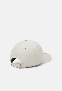 Boné de basebol cinza claro com aba curvada, tecido texturizado, detalhes costurados e uma correia ajustável na parte de trás.