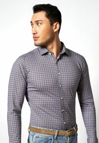 Langarmhemd in Blau mit einem geometrischen Muster in Weiß und Beige. Verfügt über einen Button-Down-Kragen und Standardknöpfe.