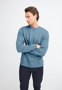 Lichtblauwe sweatshirt gemaakt van gestructureerde stof, ronde halslijn, ribgebreide manchetten en zoom. Kenmerkt zich door een klein logo op de borst.