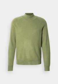 Zöld magas nyakú pulóver bordás mandzsettákkal és szegéllyel. Puha anyagból készült, sima textúrájú és laza szabású.