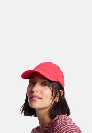Rode katoenen baseballcap met een gebogen klep en geborduurde details. Draag het met een gestreepte roze en witte shirt met korte mouwen.