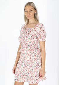 Blumenmusterkleid aus leichtem Stoff mit gerafftem Oberteil, Puffärmeln und gestuftem Rüschensaum in pastelroz, grün und lila Farbtönen.