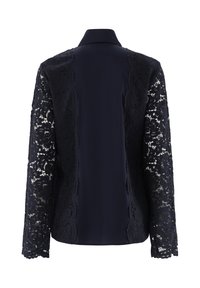 Marinebluse mit einem soliden Stoffrücken und intricatem schwarzen Spitzenlangärmeln, ausgestattet mit einem klassischen Kragen und floralem Spitzenmuster.