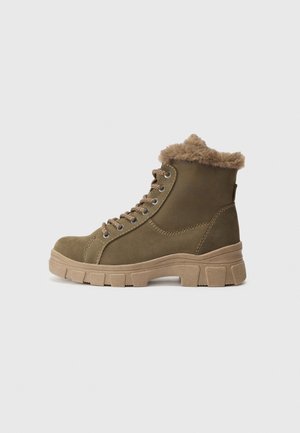 Bottes à chevilles en suede marron avec bordure en fausse fourrure, œillets en métal et semelles épaisses beiges. Comprend des lacets et un col rembourré pour plus de confort.