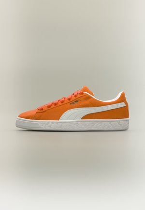 Pomarańczowy zamszowy sneaker Puma z białą podeszwą i paskiem, sznurowany, pokazany z boku na neutralnym tle.