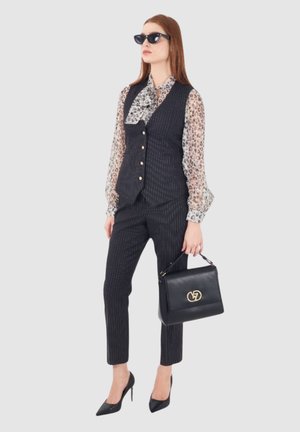 Gilet e pantaloni a righe nere abbinati a una blusa con stampa leopardata. Accessoriato con occhiali da sole neri e una borsa nera con hardware dorato.