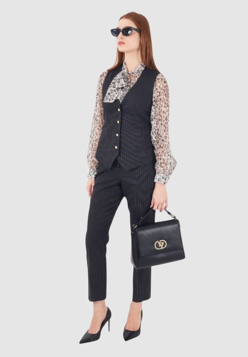 Gilet e pantaloni a righe nere abbinati a una blusa con stampa leopardata. Accessoriato con occhiali da sole neri e una borsa nera con hardware dorato.