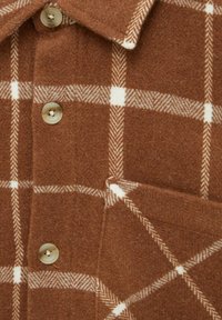 Brązowa koszula w kratę z teksturowanej mieszanki wełny, z kołnierzykiem w szpic, białymi krateczkami i zapięciem na guziki wykonanymi z jasnego plastiku.
