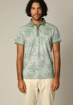 Polo à manches courtes en vert clair, doté d'un motif texturé, d'un col vert plus foncé, de deux boutons et d'un petit logo sur la poitrine.