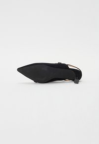 Svarte semskede slingback-sko med spiss tå, som har en slank hæl og teksturert såle. Detaljene inkluderer en liten bakrem.