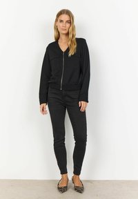 Zwarte bomberjack met ritssluiting en twee voorkasten, gecombineerd met slim-fit zwarte jeans en pointed toe zebra-print ballerina's.