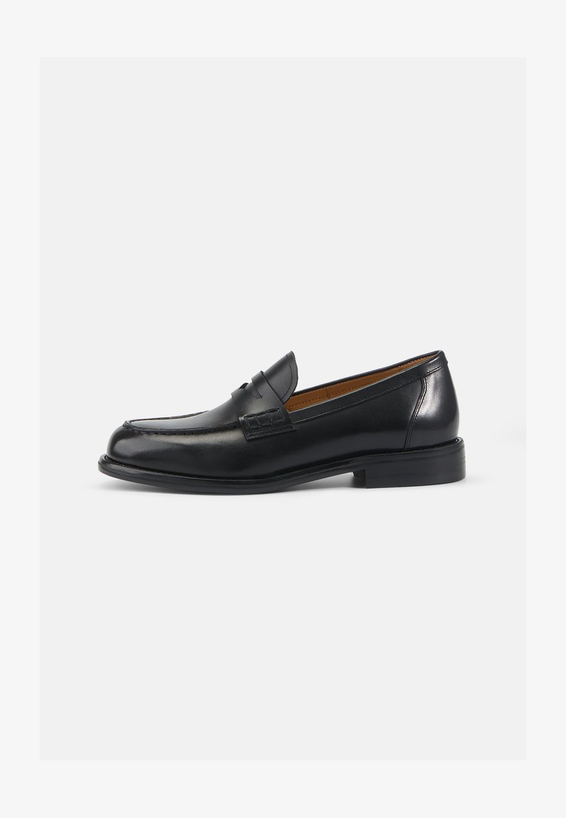 Mocassins en cuir noir avec une finition lisse, un talon bas, des détails cousus et une sangle décorative sur le devant. Design classique.