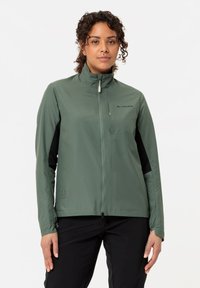 Giacca leggera di colore verde oliva con colletto alto, pannelli neri laterali e zip frontale. Presenta un logo sulla parte superiore sinistra.