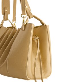 Beige Leder Eimer Tasche mit einer strukturierten Oberfläche, goldenen Hardware, verstellbaren Trägern und Kordelzugverschluss. Verfügt über eine strukturierte Form.
