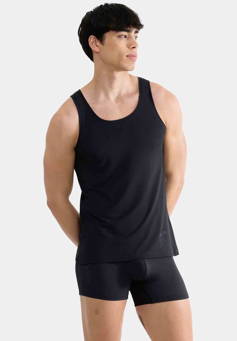 Débardeur noir en tissu lisse, doté d'un col rond et d'un design sans manches, accompagné d'un short noir moulant.