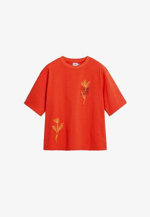 Punane puuvillane T-särk lühikeste varrukatega, mille esiküljel on kollased tikitud lillemotiivid ja tekst "MULLE MEELDIB, KES MA OLEN."