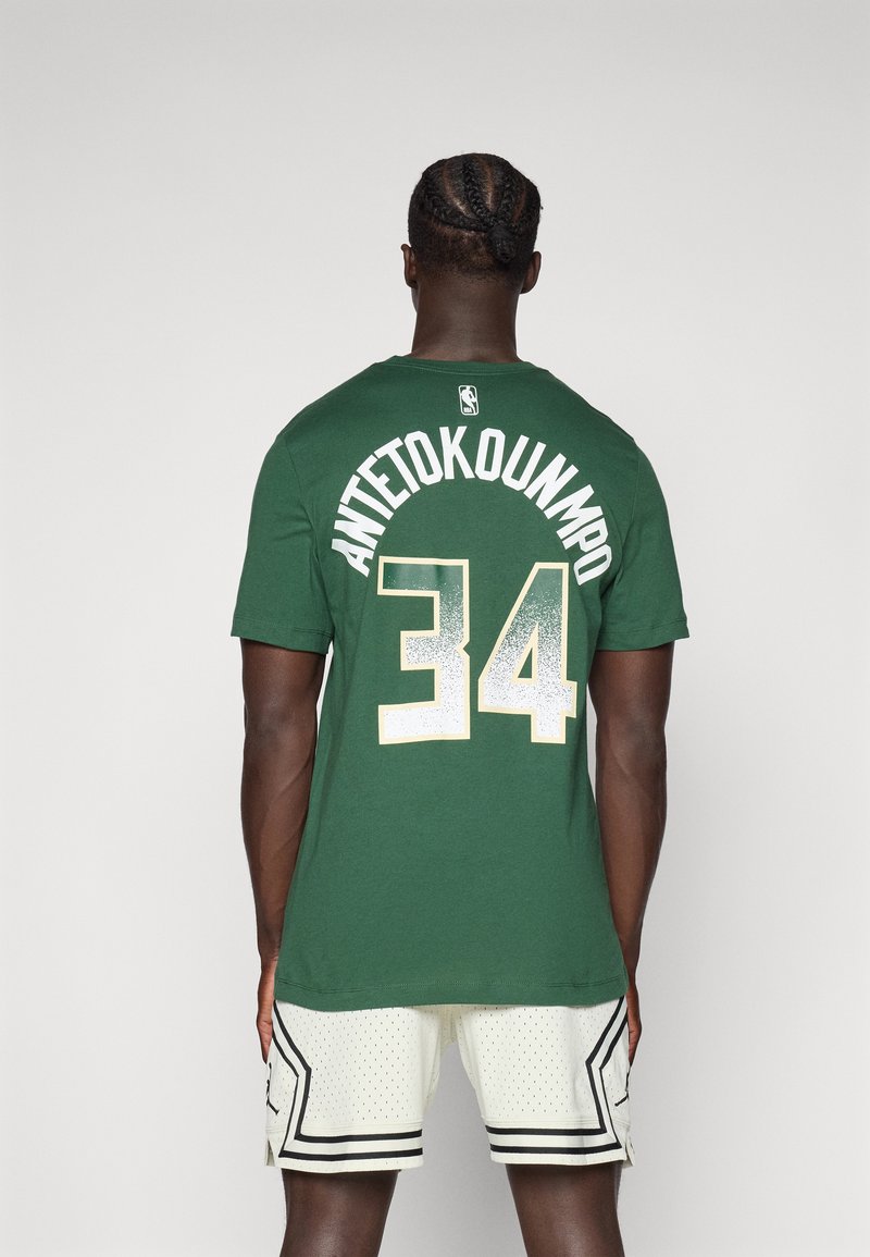 Žalias marškinėliai su užrašu "ANTETOKOUNMPO" ir numeriu "34" ant nugaros, turintys apvalų kaklą ir trumpas rankoves; dėvimi su baltais tinkliniais šortais.