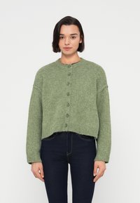 Πράσινη πλεκτή ζακέτα με στρογγυλή λαιμόκοψη, κούμπωμα με κουμπιά και μακριά μανίκια. Διαθέτει κοντό σχέδιο και ριμπ γύρω από το τελείωμα.
