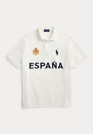Λευκό πόλο με το κείμενο "ESPAÑA", κεντημένο ισπανικό έμβλημα στο αριστερό στήθος και μαύρο λογότυπο Polo Ralph Lauren με άλογο στο δεξί στήθος.