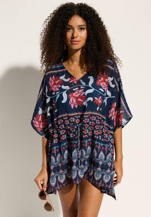 Kaftan blu navy con stampa floreale in rosa e bianco, caratterizzato da scollatura a V, maniche morbide e vita arricciata con dettaglio di laccetto.