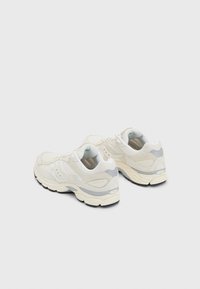 Scarpe sportive bianche con tomaia in tessuto a rete, suola ammortizzata e sottili accenti grigi. Presentano una punta rotonda e chiusura con lacci.