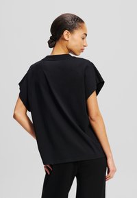 Black short-sleeve T-shirt made of cotton, featuring a loose fit and a round neckline, with a smooth texture and minimal stitching details.