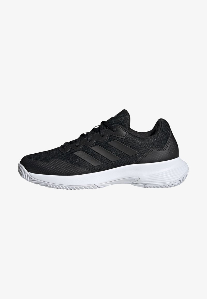 Shoe atlético preto com parte superior em malha, detalhes em couro sintético, atacadores planos e sola de borracha branca com padrão de aderência texturizado.