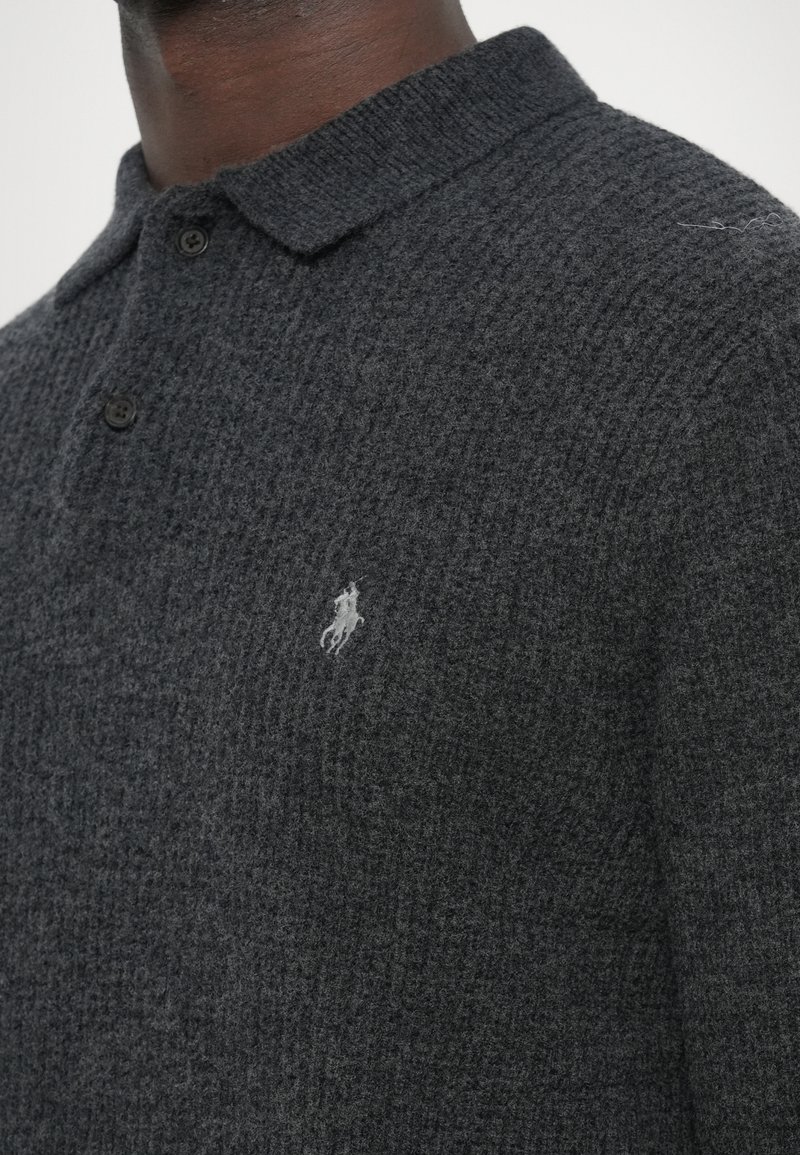 Polo in maglia grigio carbone con superficie testurizzata, colletto con bottoni e piccolo logo ricamato sul lato sinistro.