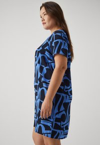 Μπλε και μαύρο φόρεμα με σχέδιο, κοντά μανίκια και χαλαρή εφαρμογή, που διαθέτει αφηρημένα σχήματα και υφή υφάσματος.