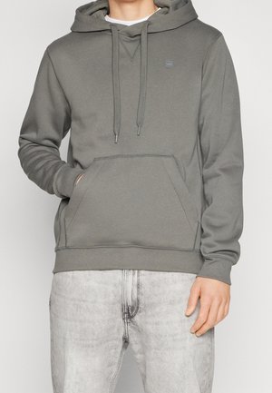 Sweatshirt à capuche gris avec poche kangourou, capuche à cordon et poignets côtelés. Le tissu a une texture lisse et une légère élasticité.