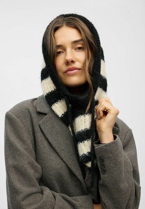 Bufanda de punto con rayas alternas en negro y crema, combinada con un blazer gris texturizado. La bufanda tiene un aspecto suave y cálido.