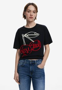 Musthave musta lühike t-särk, millel on punased ja valged tikitud kirsi ja tekstidisain. Lühikesed varrukad, vaba lõige ja puuvillane kangas.