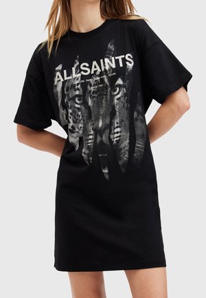 Femme portant une robe T-shirt noire oversize avec un motif de visage de tigre et le texte « ALL SAINTS » sur le devant.
