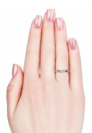 Anello in argento a forma di chevron con piccole pietre, mostrato su una mano con unghie di un rosa chiaro e lucido. La mano è rilassata con le dita leggermente aperte.