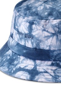 Bucket-hatt i blått tie-dye-mönster, tillverkad av bomull, med ett enfärgat blått band och diskret broderad branding på sidan.