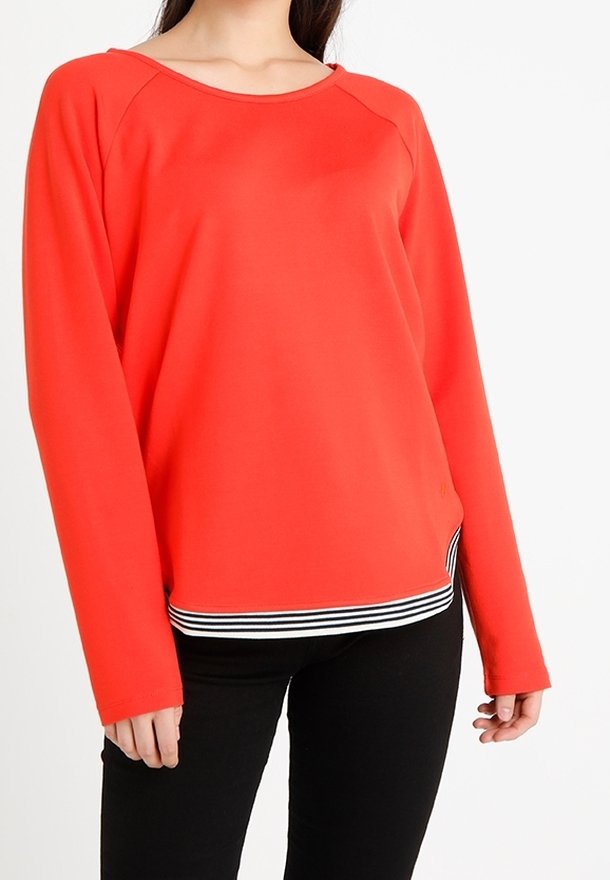 Sudadera roja de manga larga con cuello redondeado y bajo a rayas en blanco y negro. Textura suave y corte relajado.