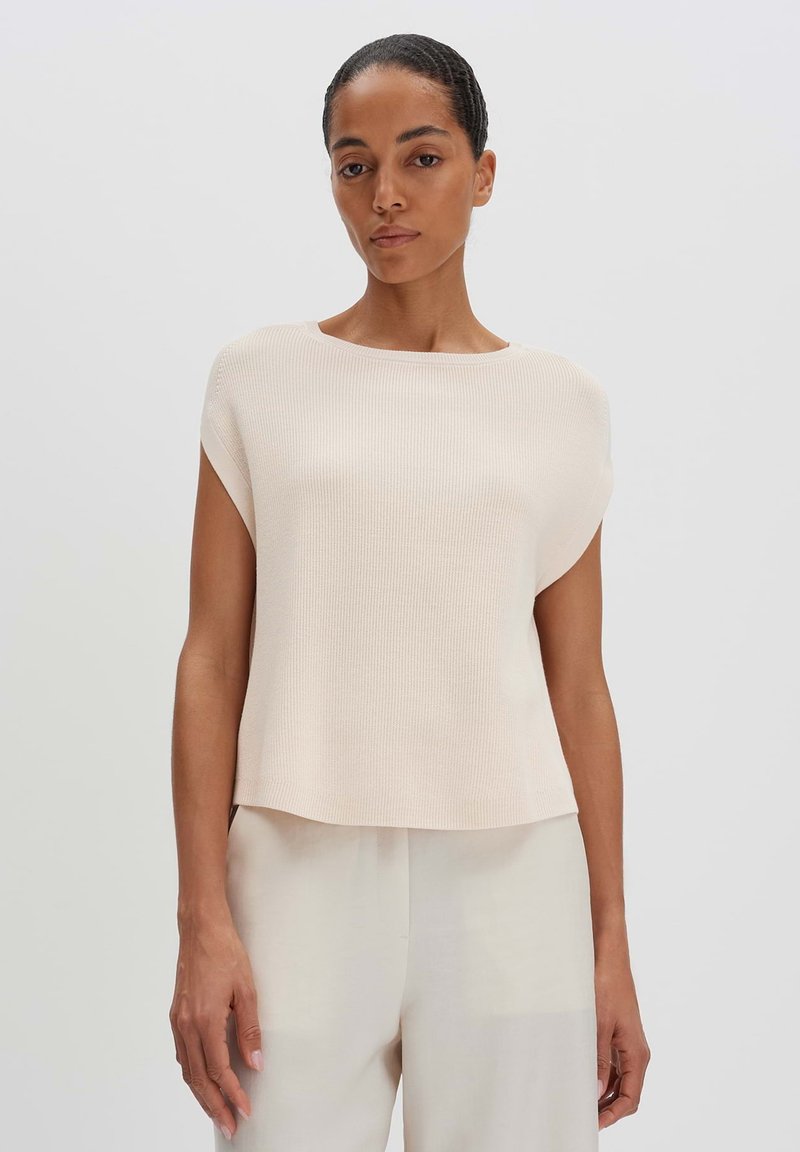 Top in tessuto a coste di un delicato rosa pallido, con scollatura rotonda e maniche corte, caratterizzato da una vestibilità ampia che si adagia sul corpo.