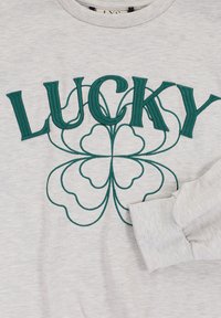 Grijze sweatshirt met groene geborduurde tekst "LUCKY" en een ontwerp van een klavertje vier. De stof heeft een zachte, gestructureerde afwerking.