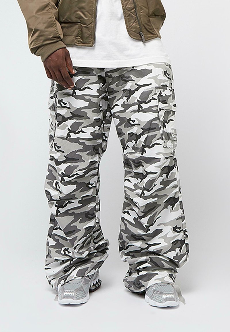 Kargo kalhoty v šedém maskáčovém vzoru s několika kapsami. Vyrobeny z lehké tkaniny, mají uvolněný střih a elastické manžety.