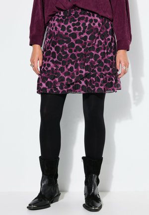 Minifalda con volantes estampada de leopardo en púrpura y negro, combinada con medias negras y botas negras hasta la mitad de la pantorrilla, acompañada de un top de manga larga color ciruela.