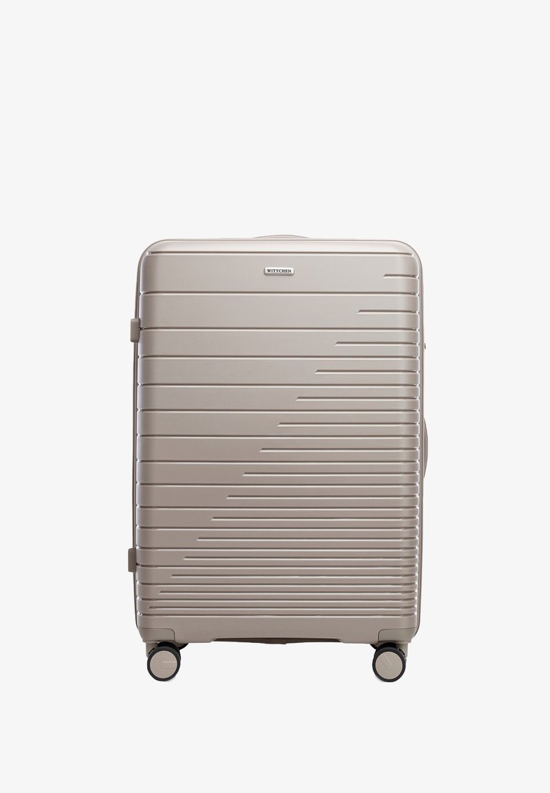 Grande valigia rigida in beige metallico, con linee orizzontali, doppie ruote e una maniglia laterale per un facile trasporto. Logo del marchio visibile.