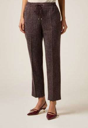 Bordeaux geklede broek met een trekkoord in de taille, taps toelopende pasvorm en zijzakken, gecombineerd met glanzende bordeaux puntige schoenen.