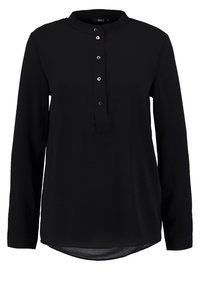 Blusa nera a maniche lunghe con colletto rotondo e una corta placca con bottoni caratterizzata da cinque bottoni metallici.