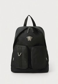 Črn najlonski nahrbtnik z dvema sprednjima žepoma na zadrgo, logotipom in nastavljivimi trakovi. Gladek tekstura z minimalističnim dizajnom.