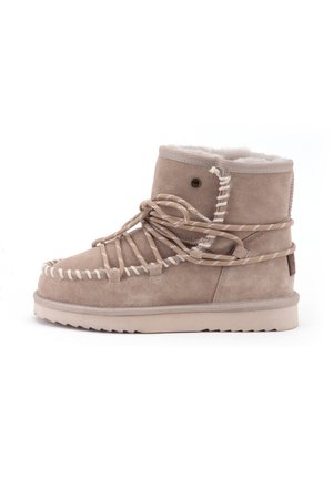 Beige suede enkellaarzen met een witte nepbont voering, decoratieve veters en een getextureerde rubberen zool. Contrasterende stiksels voegen detail toe.