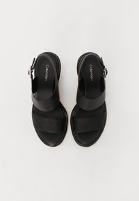 Sandalias negras con un upper de cuero suave, que presentan correas anchas y una banda texturizada. Un acento de hebilla y una plantilla acolchada completan el diseño.