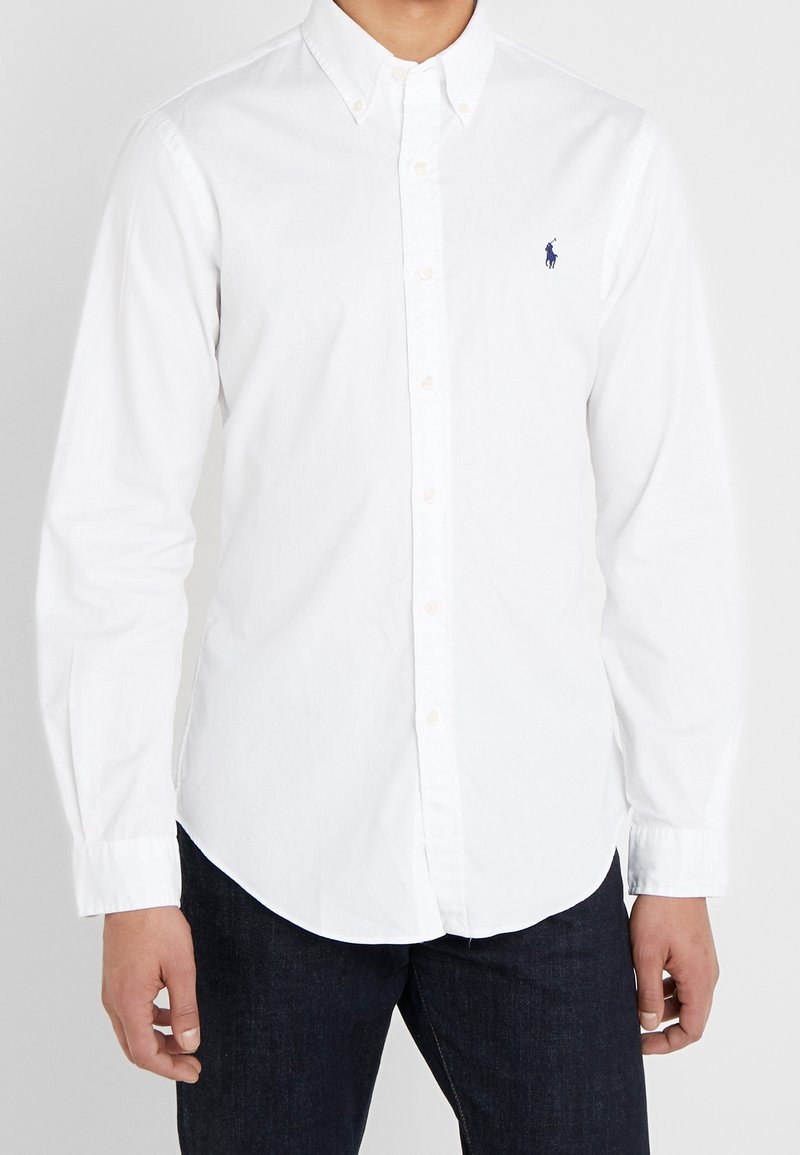 Biała bawełniana koszula zapinana na guziki, z długimi rękawami, klasycznym kołnierzykiem i małym haftowanym logo na lewej piersi.