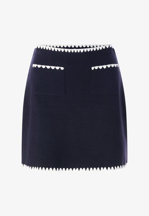 Tengerészkék ceruzaszoknya testhezálló szabással, fehér hullámos szegéllyel a derékrésznél és az alján, elől két hullámos szegélyű zsebbel.