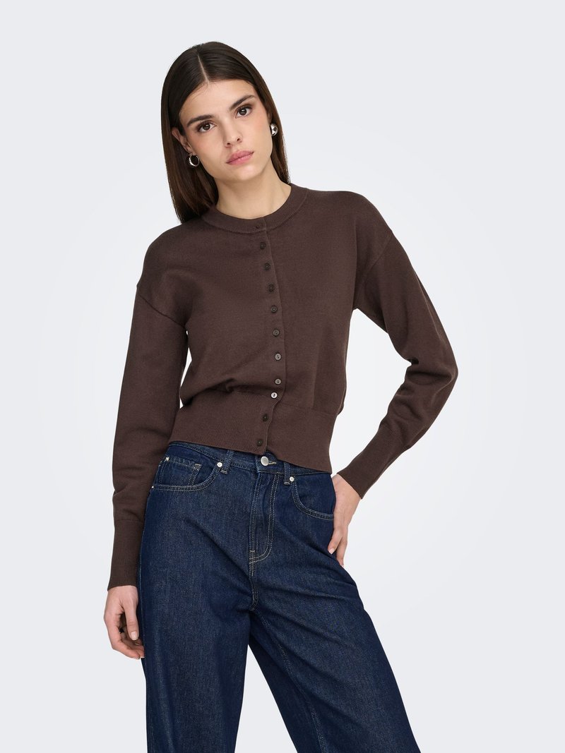 Bruine gebreide cardigan met een ronde halslijn en knoopsluiting aan de voorkant. Gecombineerd met hoge taille blauwe spijkerbroek. Zachte textuur, ontspannen pasvorm.