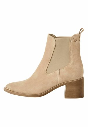 Beige mockasinstövlett med blockklack, elastisk sidopanel, dragflik och metallicdetalj på tåspetsen.